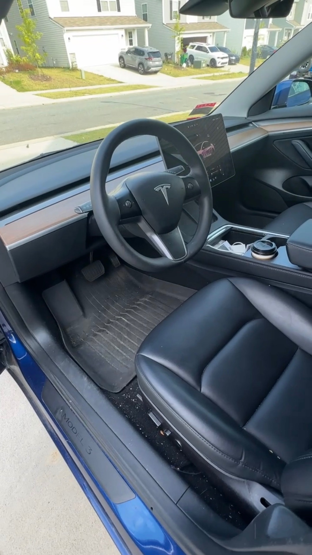 Tesla Model 3 interior before detailing — dirty floor mats and debris